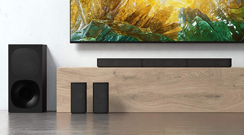 Hệ thống loa rạp hát tại nhà màu đen gồm loa thanh, loa siêu trầm và hai loa vệ tinh đặt dưới TV